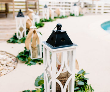 a white lantern with greenery on the ground