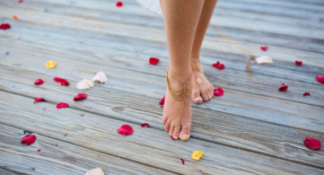 a woman standing on a wooden deck with rose petals